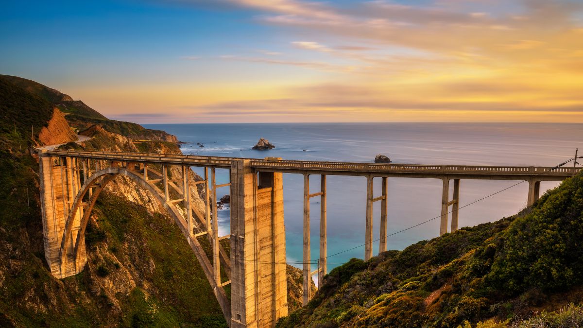 A panoramic photo of a bridge with a view of the ocean