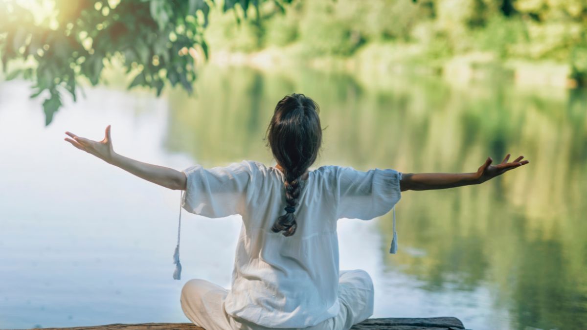 A woman meditating by the river